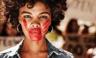 Stoppt Gewalt gegen Frauen. Foto: Frauengesicht mit roter aufgemalter Hand über dem Mund. Adobe Stock | Jacob Lund | 211192026