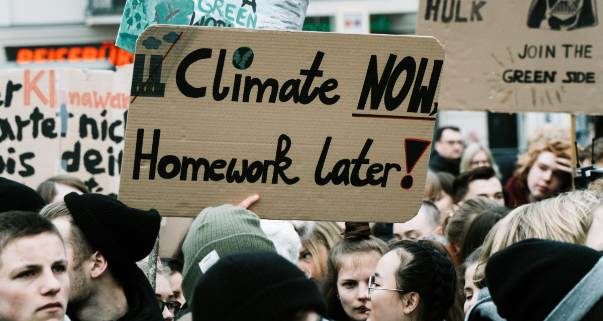 Schüler bei einer Demonstration gegen Klimawandel halten Plakat mit dem Schriftzug "Climate now, Homework later" (Übersetzung: Klima jetzt, Hausaufgaben später) hoch.