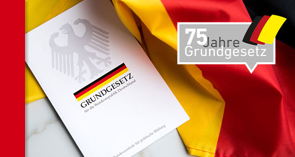75 Jahre Grundgesetz. Foto: Grundgesetz-Buch der Bundesrepublik Deutschland auf Flagge. Adobe Stock | Christin Klose + LpB-Logo 75 Jahre GG.