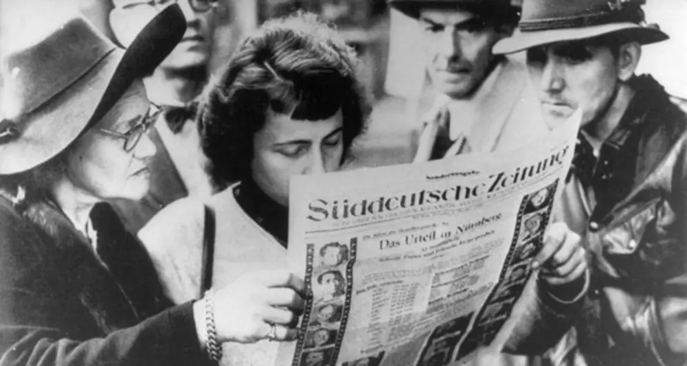 Interessierte Zeitungsleser nach der Urteilsverkündung der Nürnberger Prozesse. Foto: Bundesarchiv, Bild 146-1990-032-29A / Unknown / CC-BY-SA 3.0. Interessierte Zeitungsleser nach der Urteilsverkündung der Nürnberger Prozesse. Foto: Bundesarchiv, Bild 146-1990-032-29A / Unknown / CC-BY-SA 3.0.