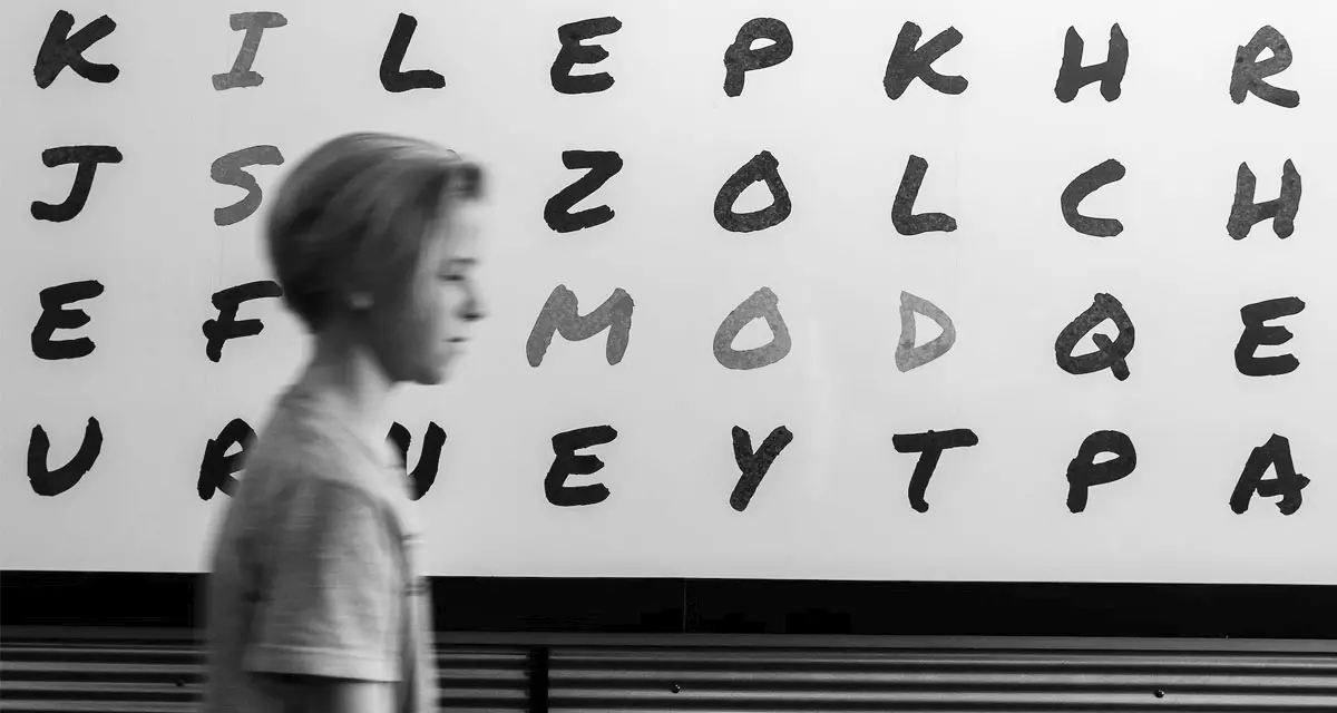 Mensch läuft an Wand mit Buchstaben vorbei. Symbolfoto Analphabetismus. Foto: unsplash.com | John Jennings.