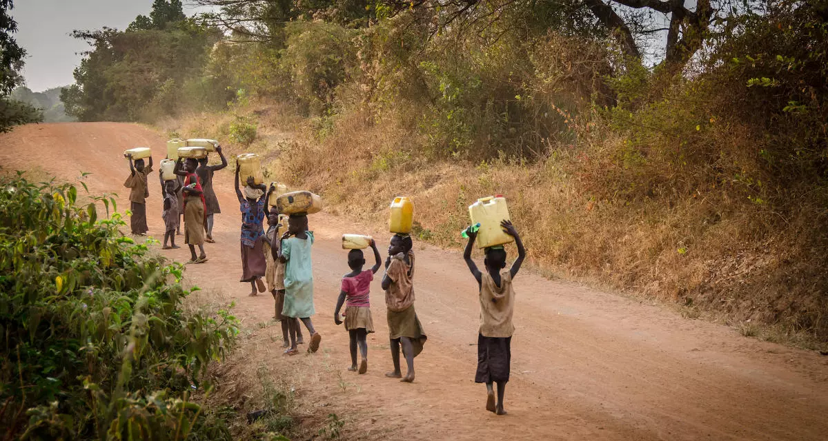Frauen und Kinder in Uganda auf dem Rückweg vom Wasserholen.