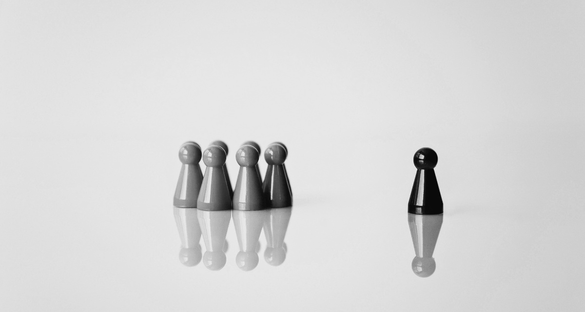 Schwarz-Weiß-Bild. Eine Gruppe von Spielfiguren, rechts daneben eine einzelne weitere Spielfigur.
