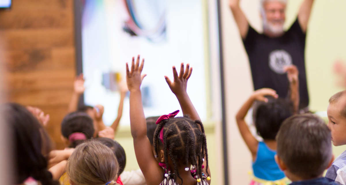 Kinder und ein Erwachsener recken ihre Arme in die Höhe.