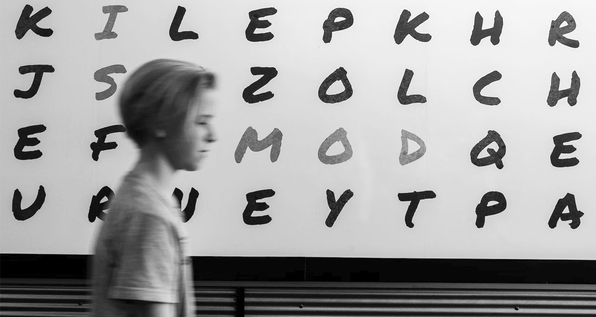 Mensch läuft an Wand mit Buchstaben vorbei. Symbolfoto Analphabetismus. Foto: unsplash.com | John Jennings.
