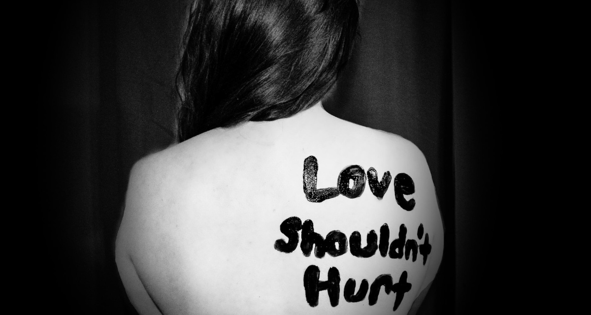 Frau mit dem Schriftzug „Love shouldn't hurt“ auf dem Rücken. Foto: unsplash.com | Sydney Sims